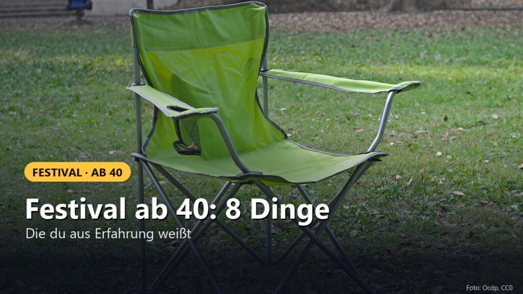 Grüner Campingstuhl mit Armlehnen und Getränkehalter auf einer Wiese