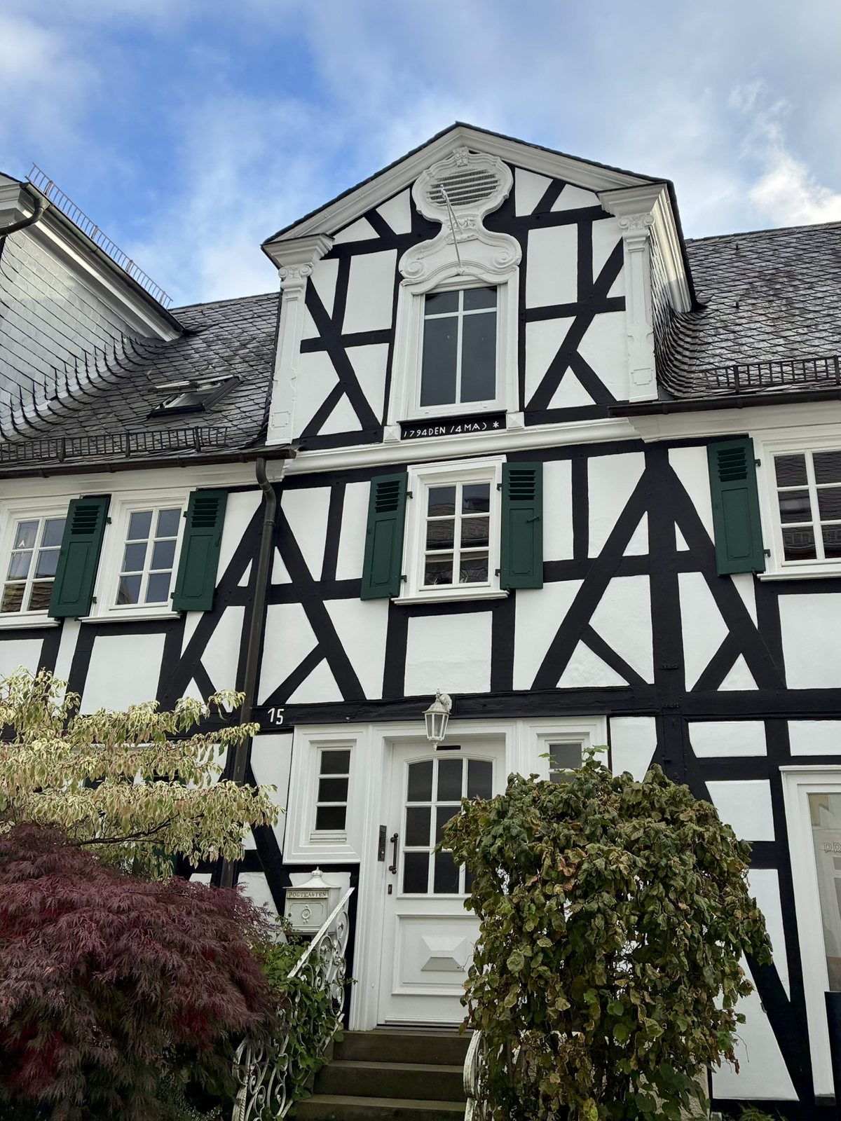 Fachwerkhaus mit verziertem Giebel und grünen Fensterläden
